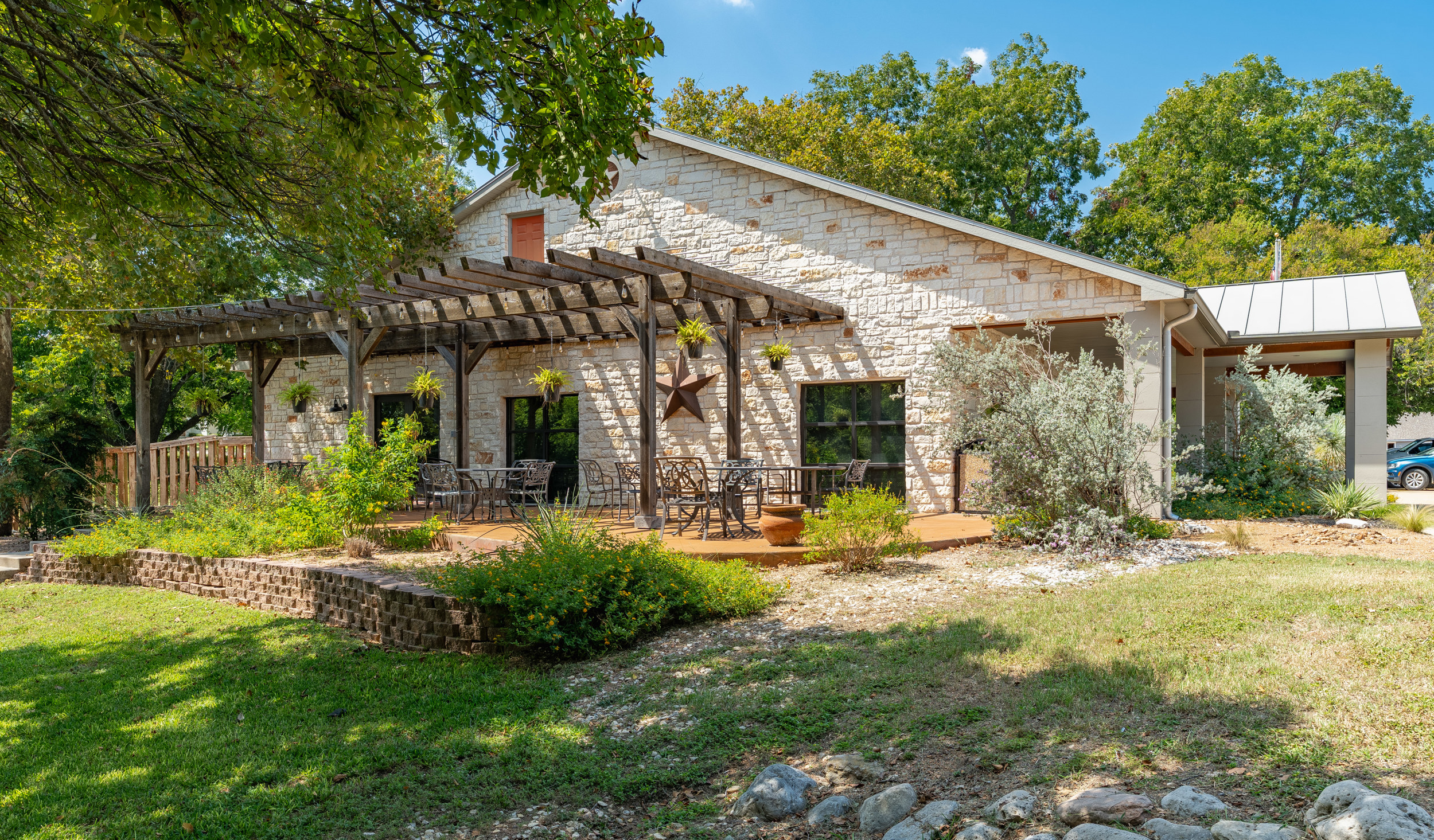 A stone building with a wooden pergola and outdoor seating area