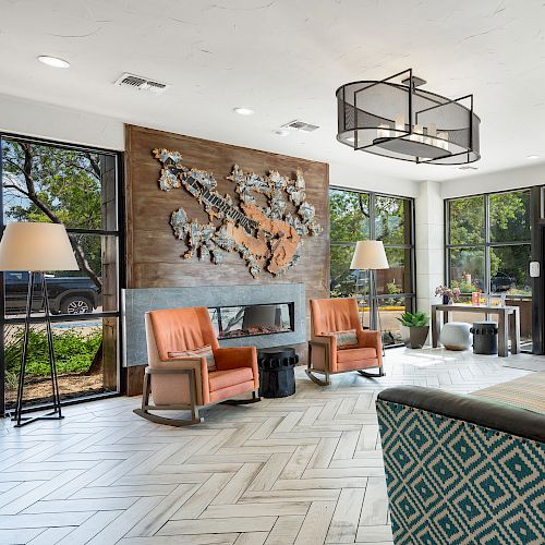 A modern lobby with seating, decorations on the wall, and large windows allowing natural light, creating a welcoming atmosphere.