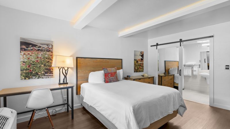A hotel room with a bed, desk, and sliding door to the bathroom.