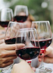A group toasting with glasses of red wine, smiling and clinking together, celebrating cheers.