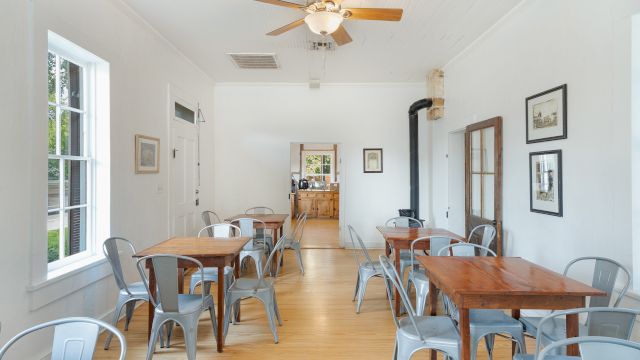 A brightly lit dining area with wooden tables and metal chairs.