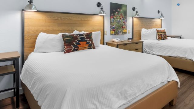 A hotel room with two beds, nightstands, and lamps