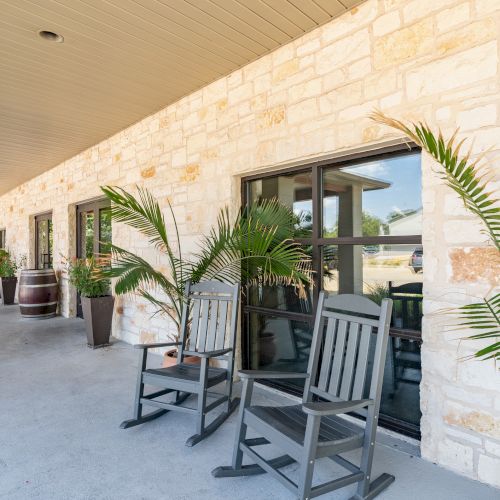 A sunny alley with bicycles parked along a stone wall, potted plants, and a shaded path.