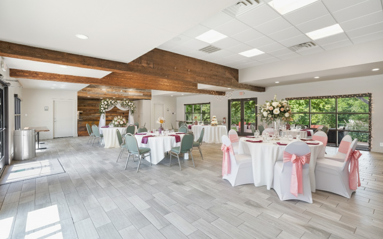 A large meeting room with round tables, white tablecloths, and pink chair covers.