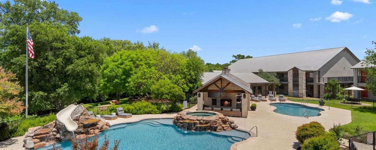 A large pool area with a water slide, fireplace, and outdoor furniture