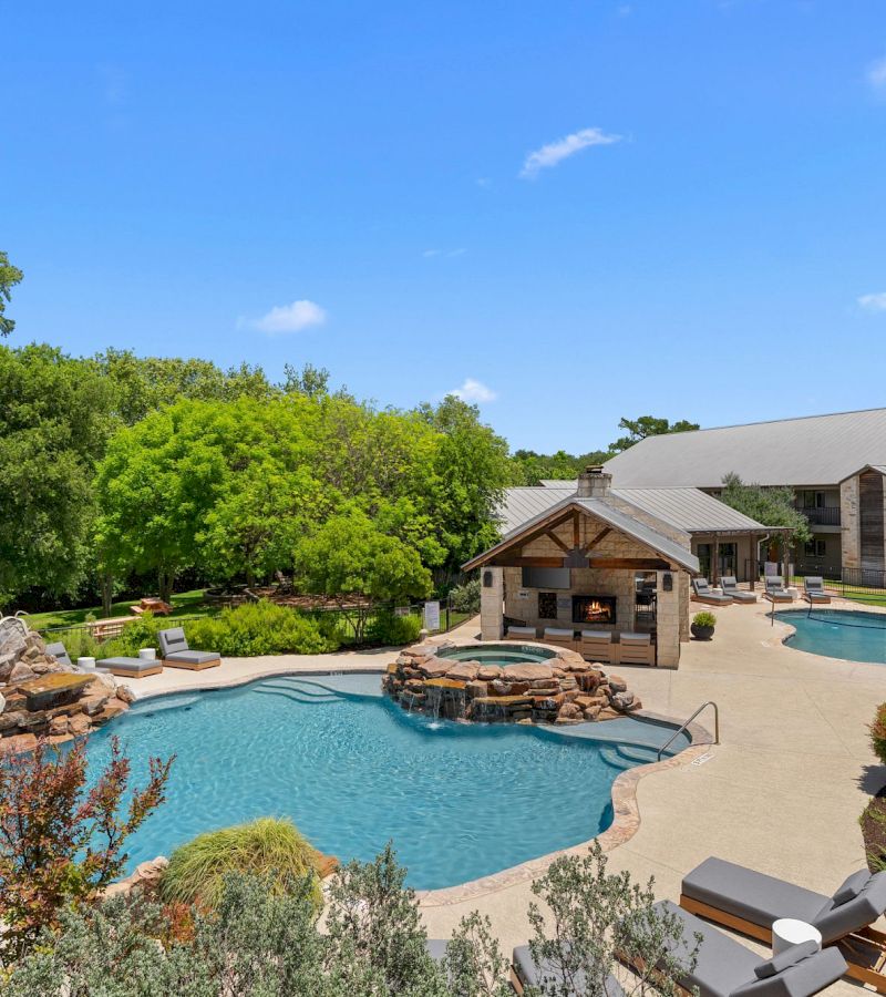 A pool area with a waterfall and fireplace